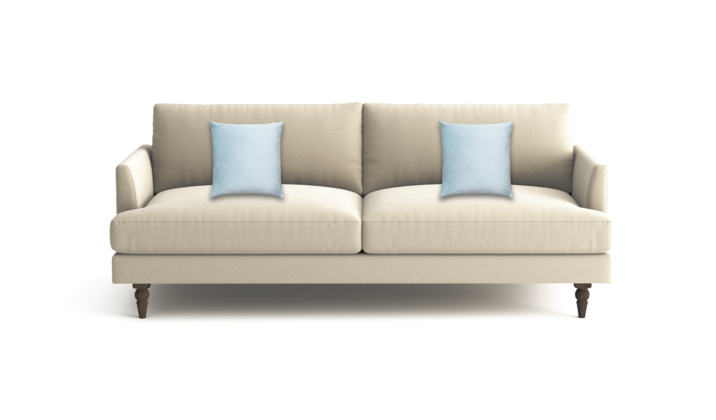 A modern two-seater sofa in a light beige fabric, styled with two light blue throw pillows and supported by dark brown wooden legs, shown against a plain white background.