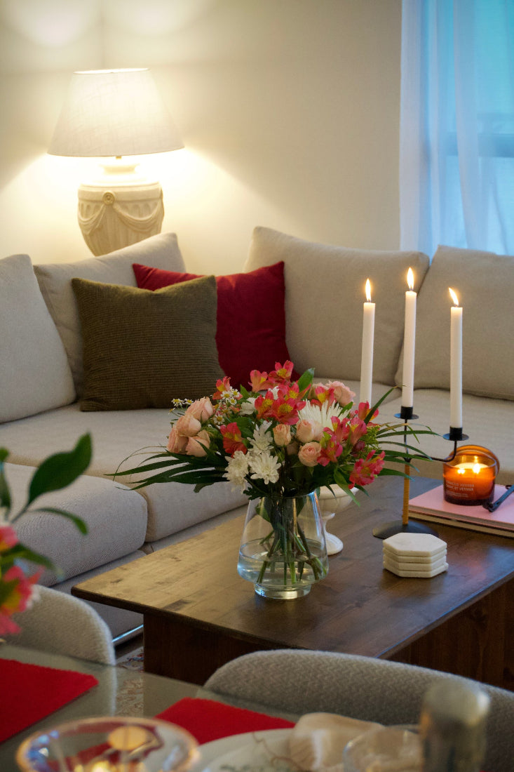 Decorative setup with candles, flowers, and books on a coffee table in a living room.