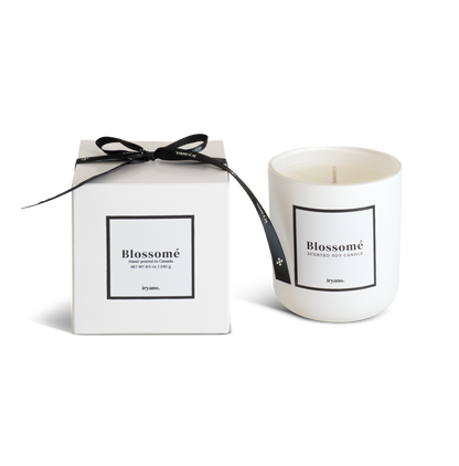 Candle with packaging labeled 'Blossomé' on a white background