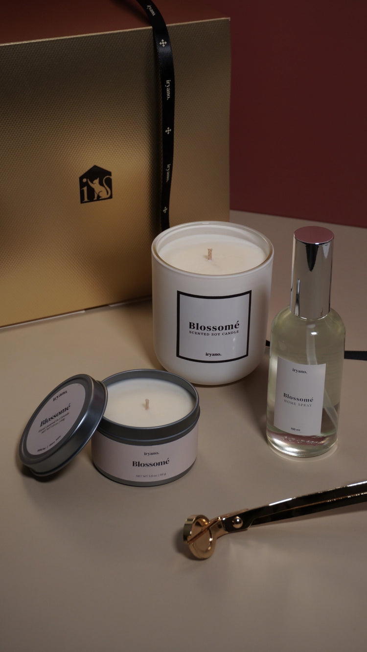 Blossom candle and perfume bottle on a table with a gold box in the background