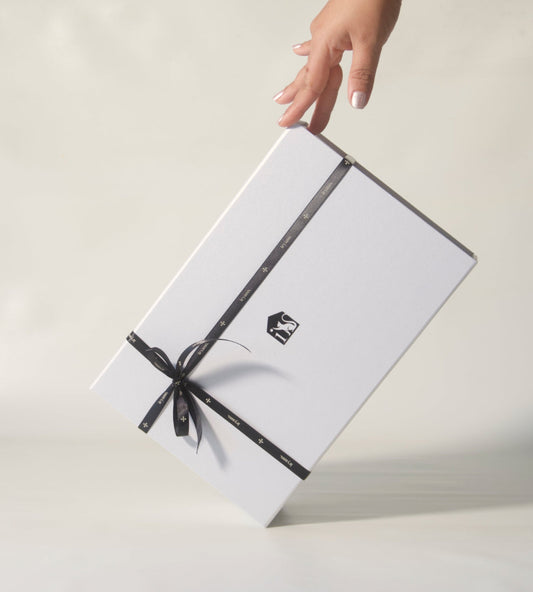 White gift box with a black ribbon held by a hand on a light background