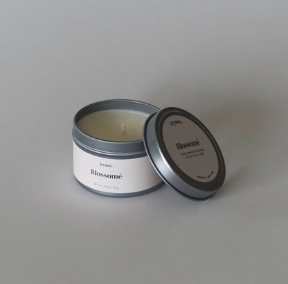 Candle in a metal tin with 'Blossom' branding on a gray background