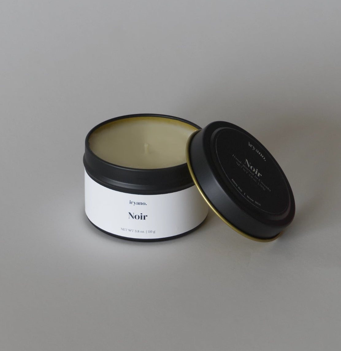 Candle jar labeled 'Noir' on a gray background