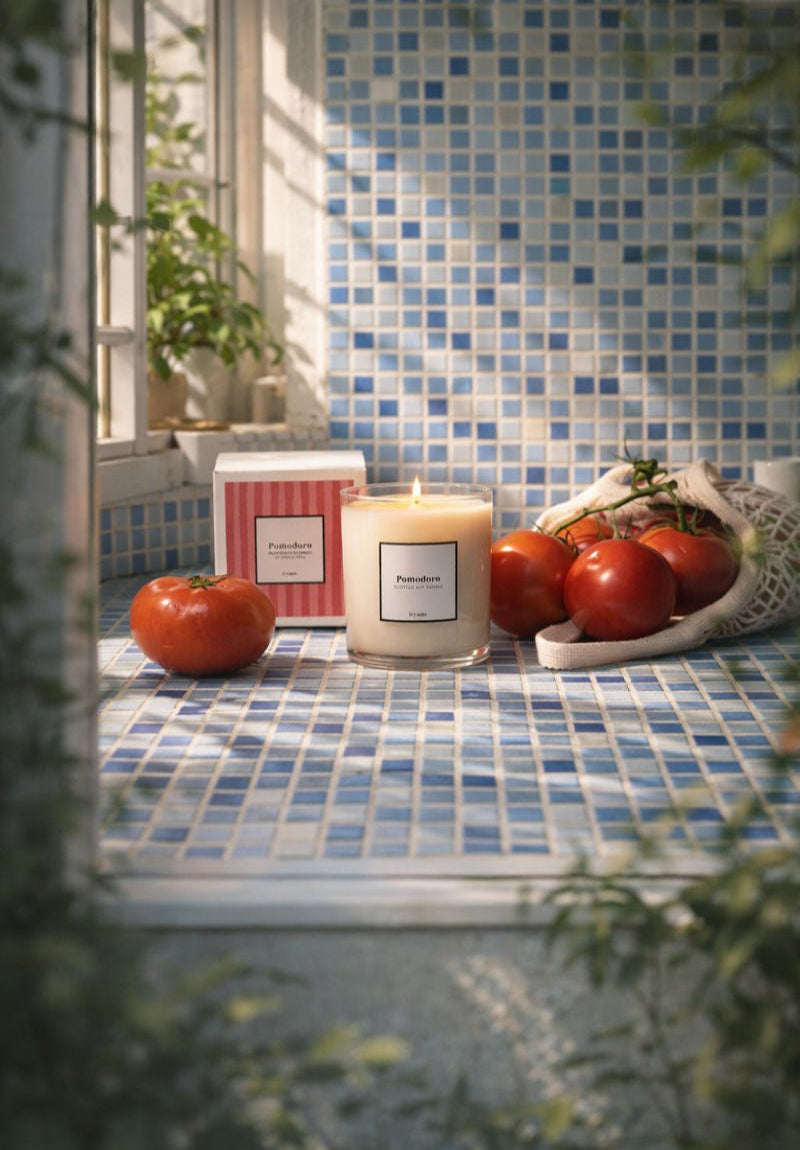 Candle with tomatoes on a tiled windowsill