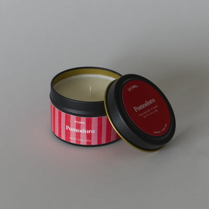 Candle in a tin with a red and white striped label on a gray background